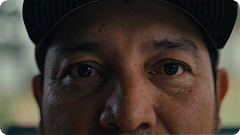 Close-up of a man's face with a focus on his eyes, wearing a black cap.